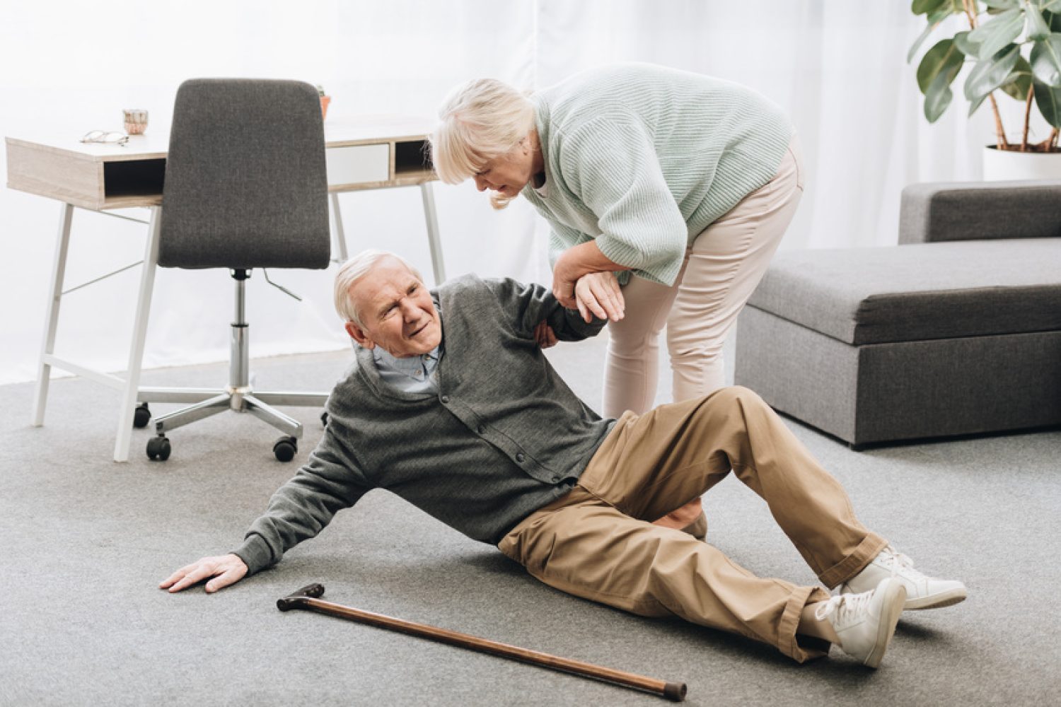 old woman helping to stand up husband who falled down on floor