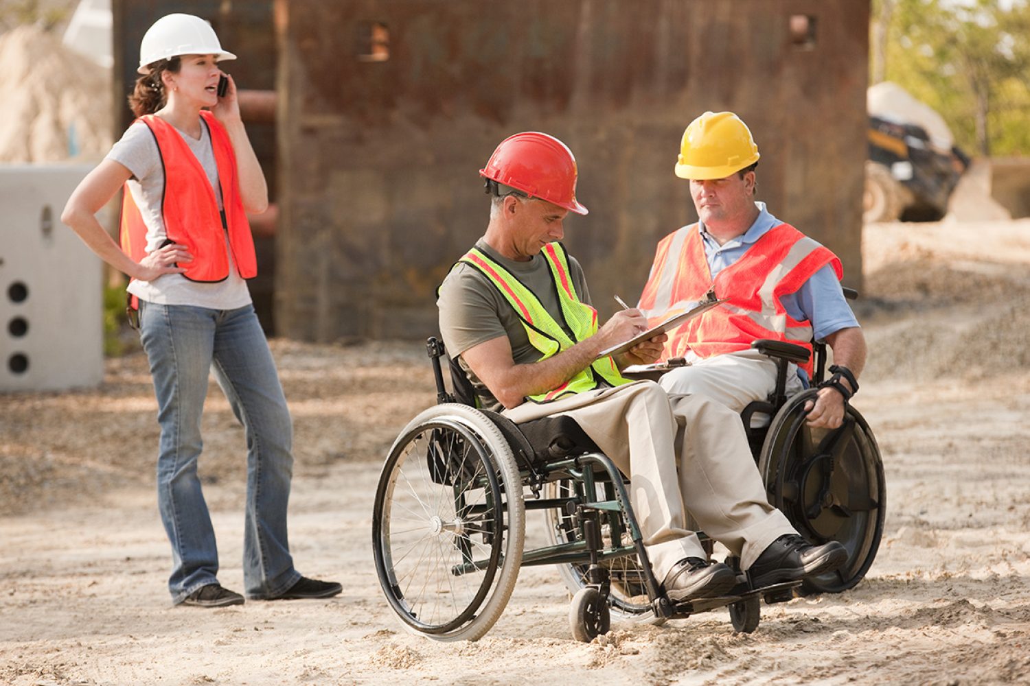 Project engineers in wheelchairs discussing plans on site