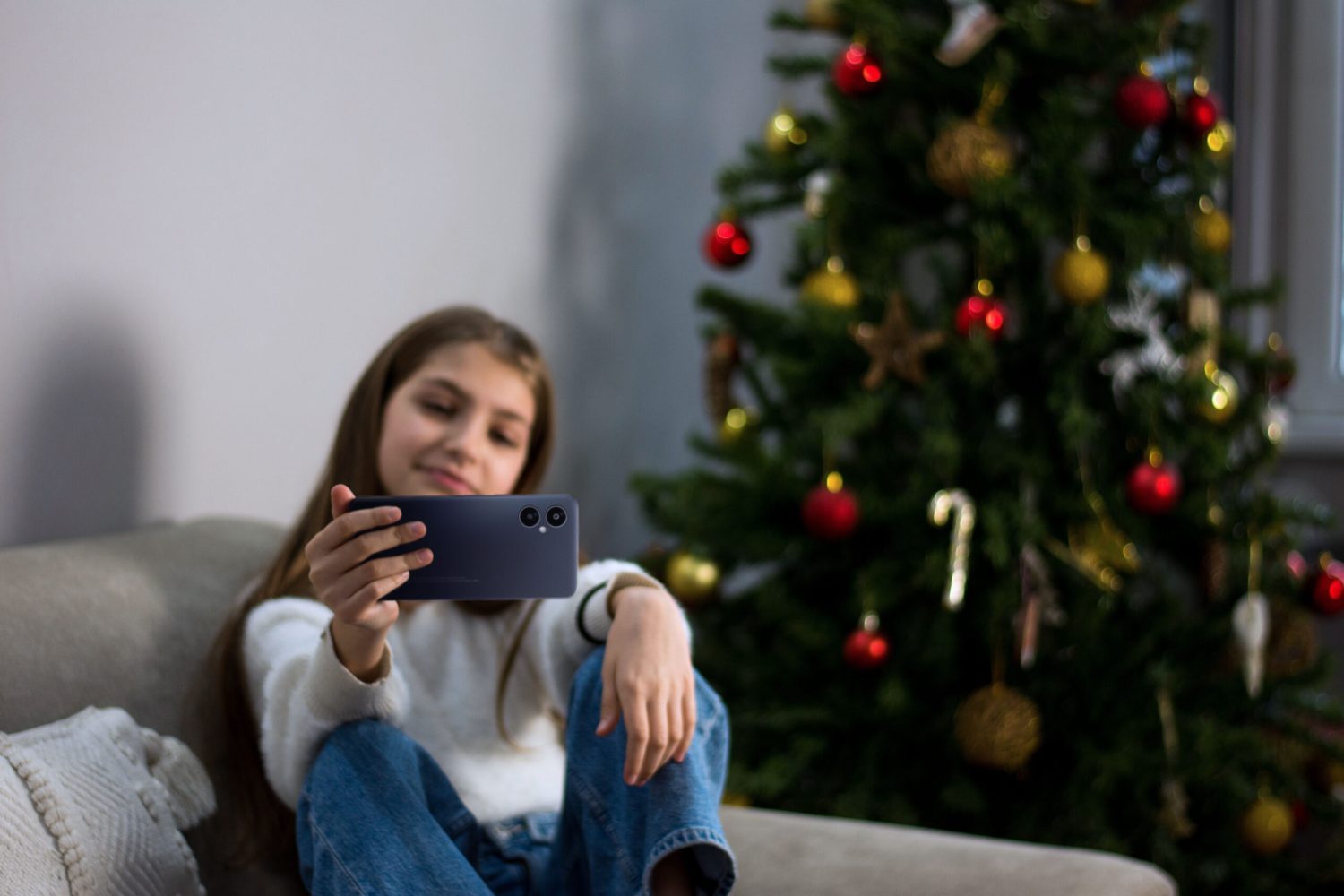 Young  girl takes a selfie in a room with a Christmas tree