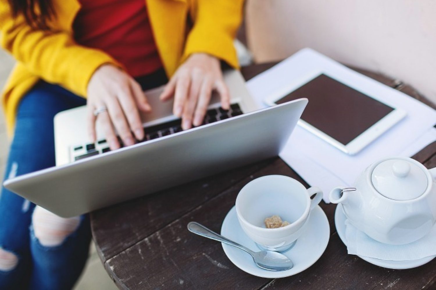 Woman hands in bright clothes with laptop tablet and tea outdoors in cafe