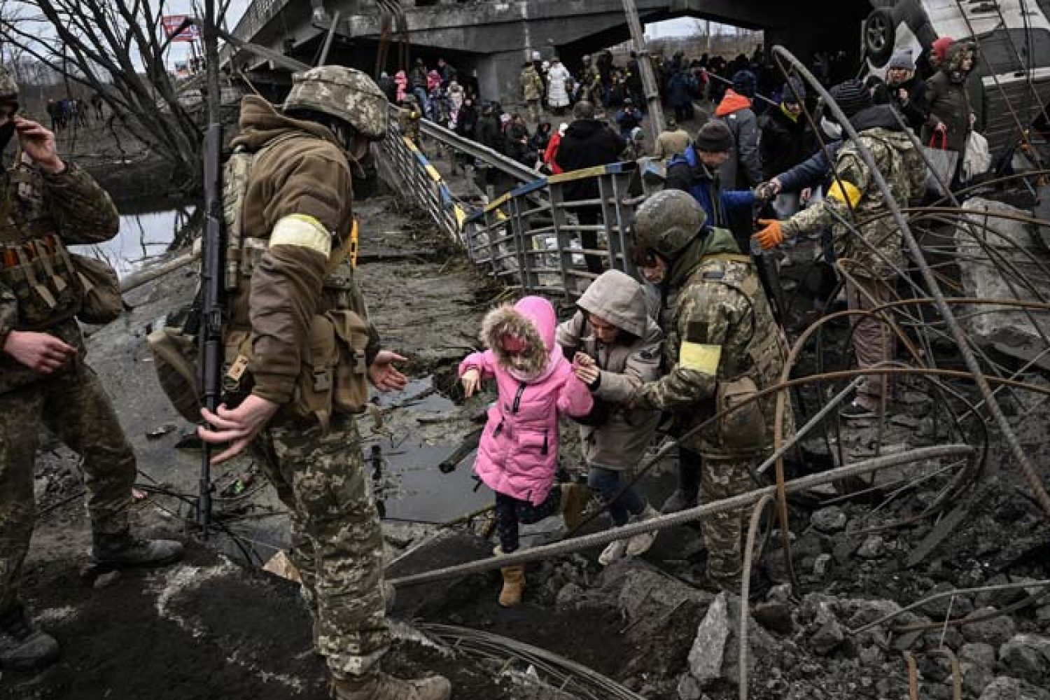 People cross a destroyed bridge as they evacuate the city of Irpin, northwest of Kyiv, during heavy shelling and bombing on March 5, 2022, 10 days after Russia launched a military in vasion on Ukraine. (Photo by Aris Messinis / AFP)
